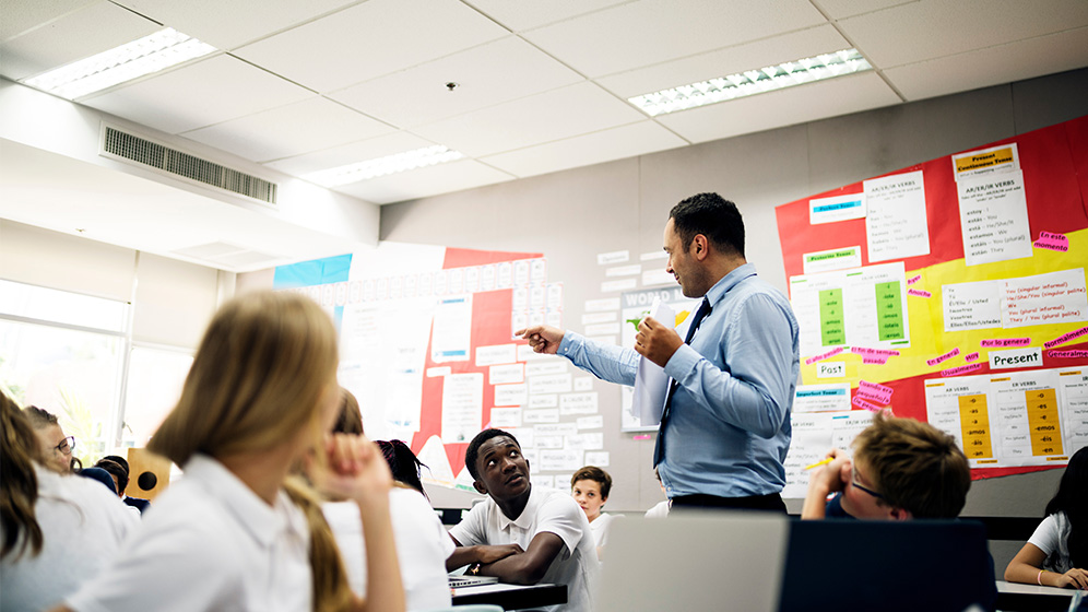 Languages teacher standing in the middle of class with students looking engaged.